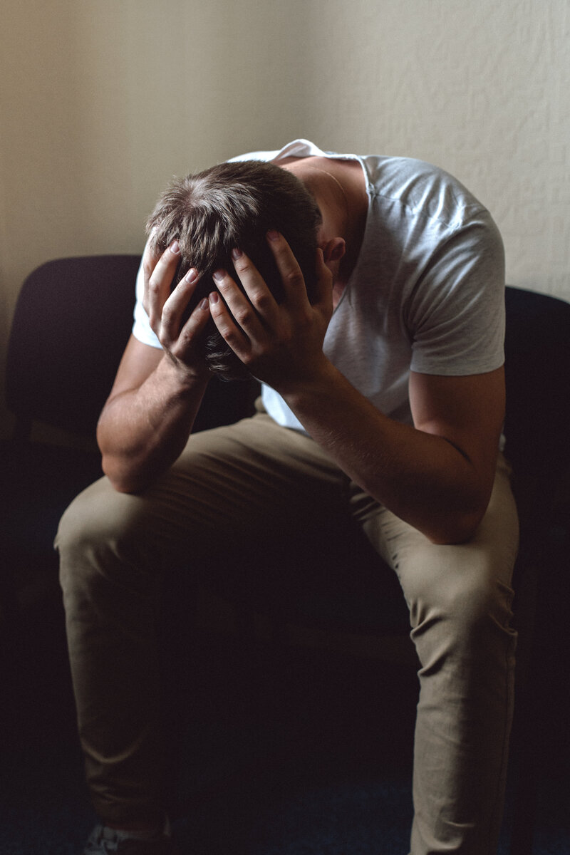 A man visibly in distress with his head in his hands, representing clients seeking help for anxiety, depression, and burnout in NYC.