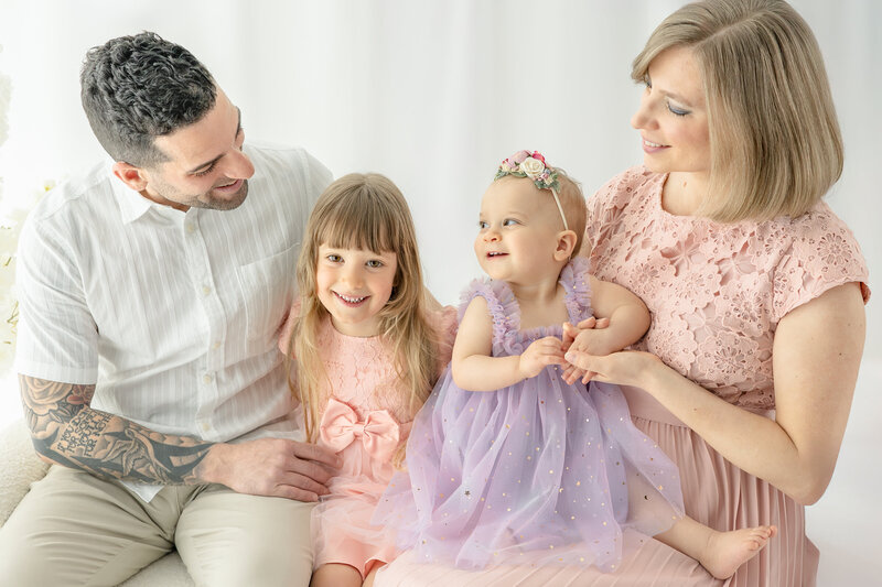 Mom and Dad tickling daughters who are seated between them — photographed by Alliston and Barrie maternity, newborn, and family photographer.