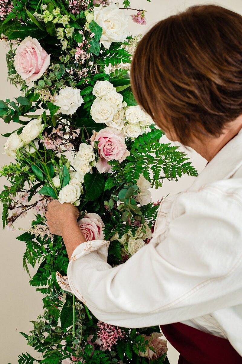 Detail photo of florist placing flowers into an arbor piece