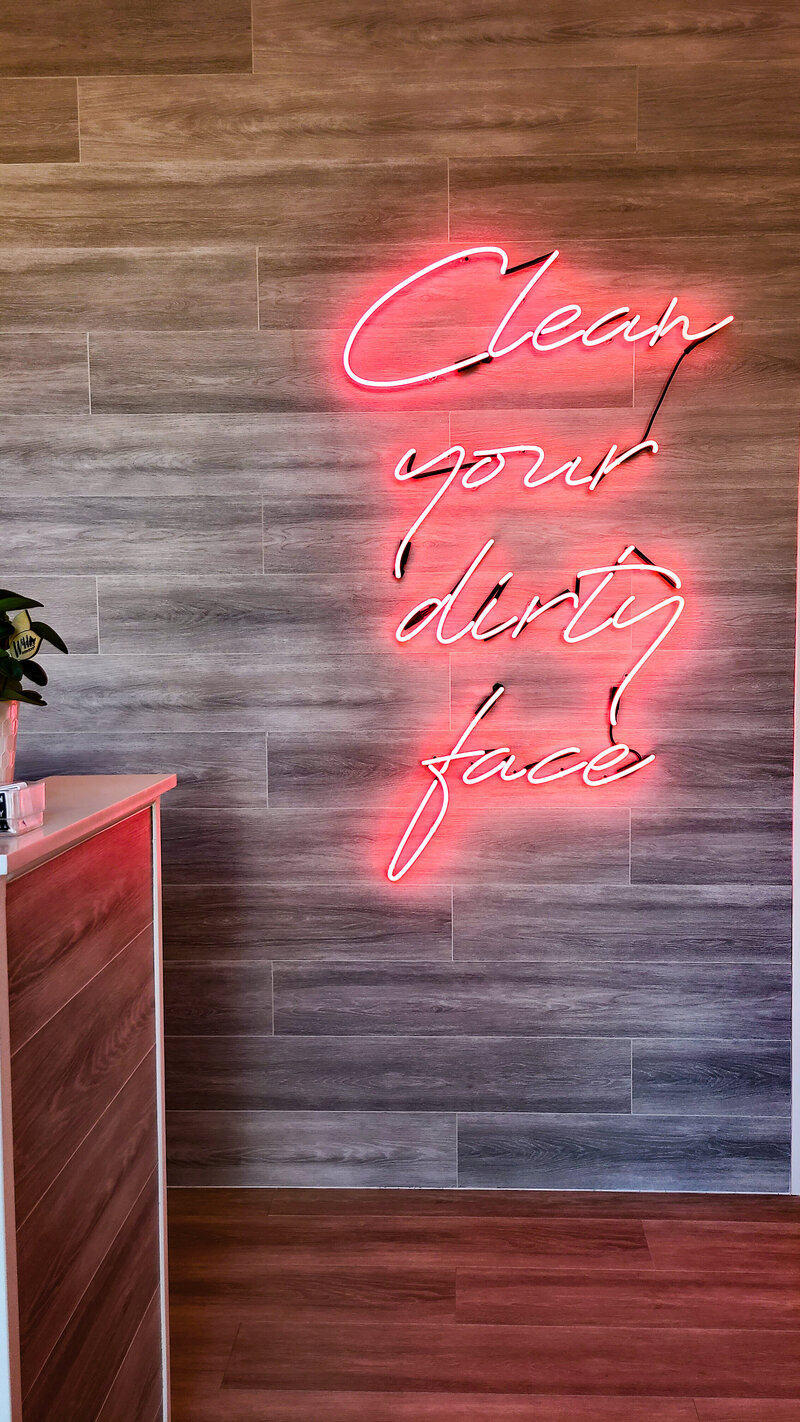 a neon sign that says clean your dirty face at the entrance of a facial spa in orlando florida for content creation socialfizz