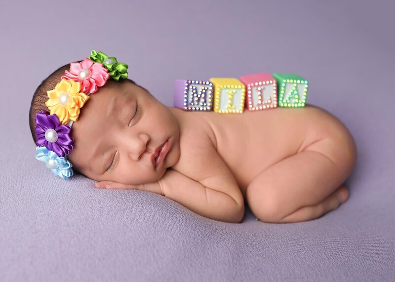 Newborn on purple blanket with her name in blocks on her back at her denver newborn photography session.