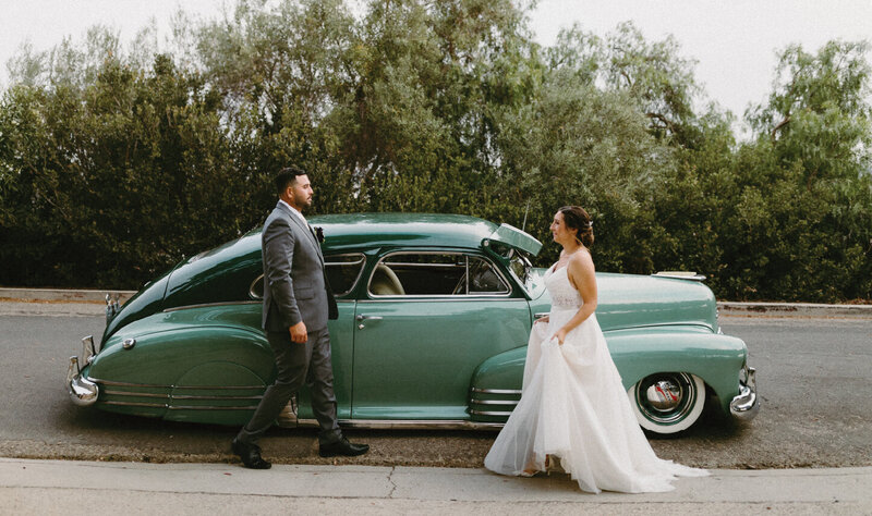 Bride and groom walking towards vintage car