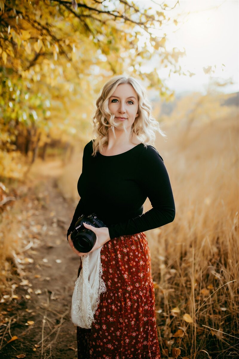 woman standing holding a camera with wind blowing in her face