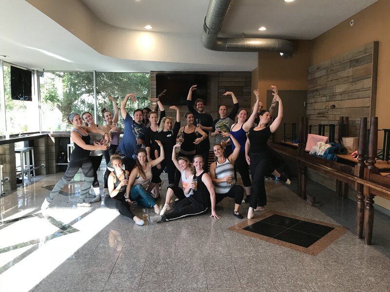 Group of people posing for a picture with their arm stretch over their heads in a ballet position