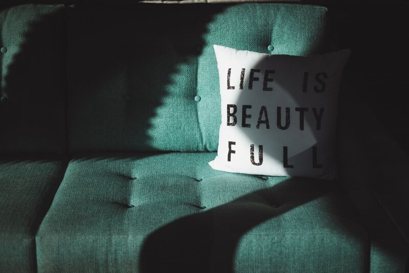 Teal couch with a cushion that says "Life is Beautiful," symbolizing financial freedom, work-life balance, and a stress-free business journey. Kim Russell’s story is a testament to building sustainable business success and financial well-being—helping entrepreneurs achieve clarity, balance, and long-term growth.