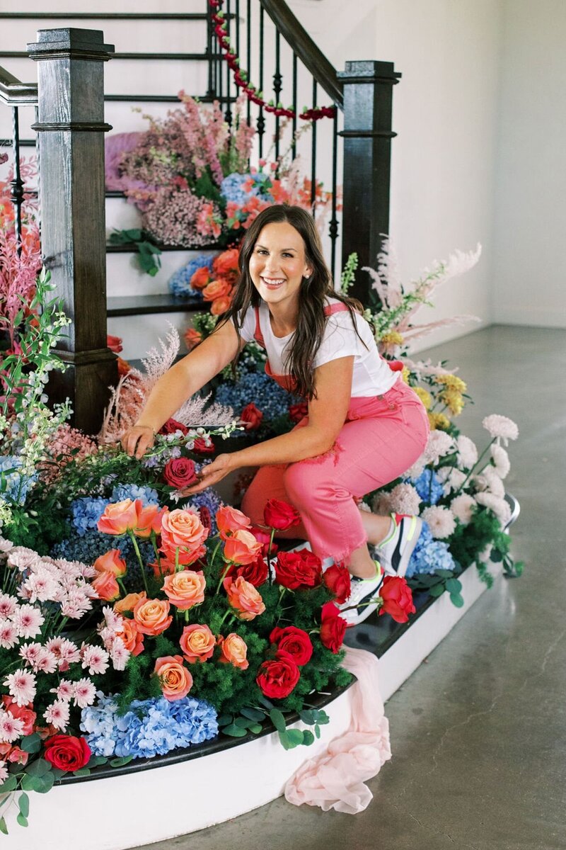 Tamara Menges arranging colorful flowers for a whimsical wedding floral installation.