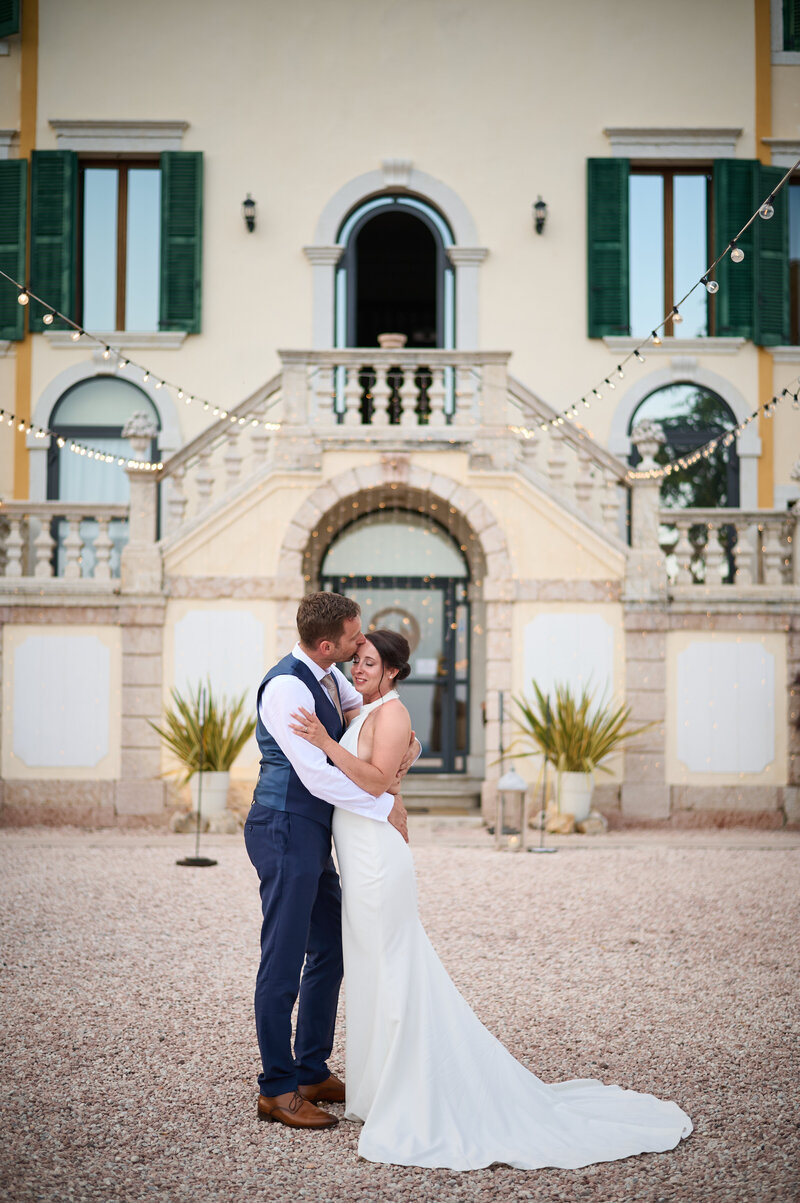 Hochzeitspaar in inniger Pose vor der Villa Cariola am Gardasee. Luxushochzeit Italien.