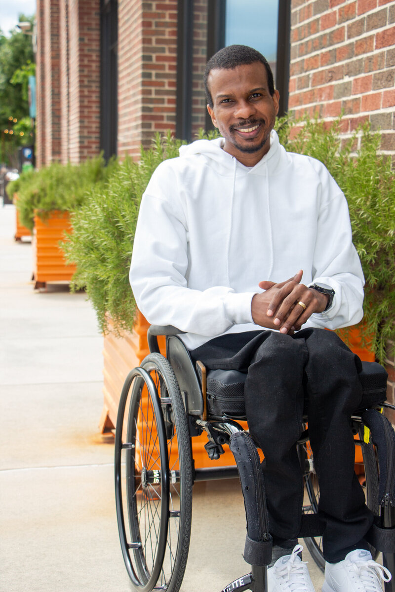 black disabled man inspirational speaker wearing white hoodie