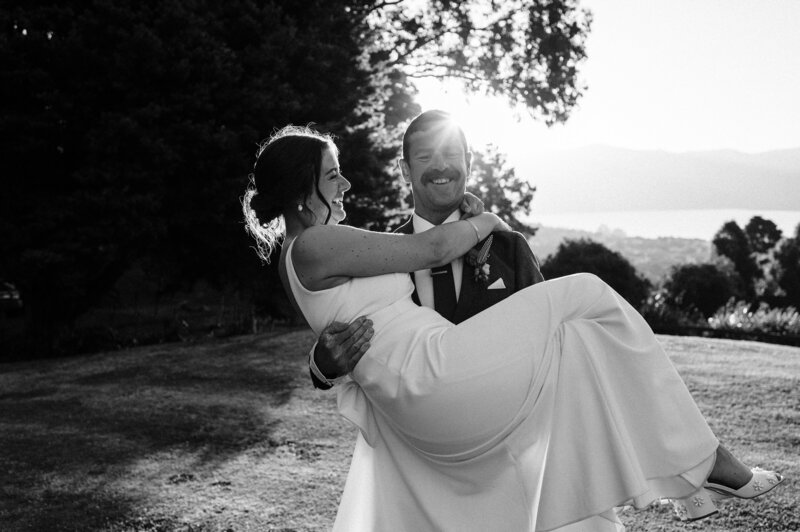 groom carries bride in sunset in akaroa at mt vernon