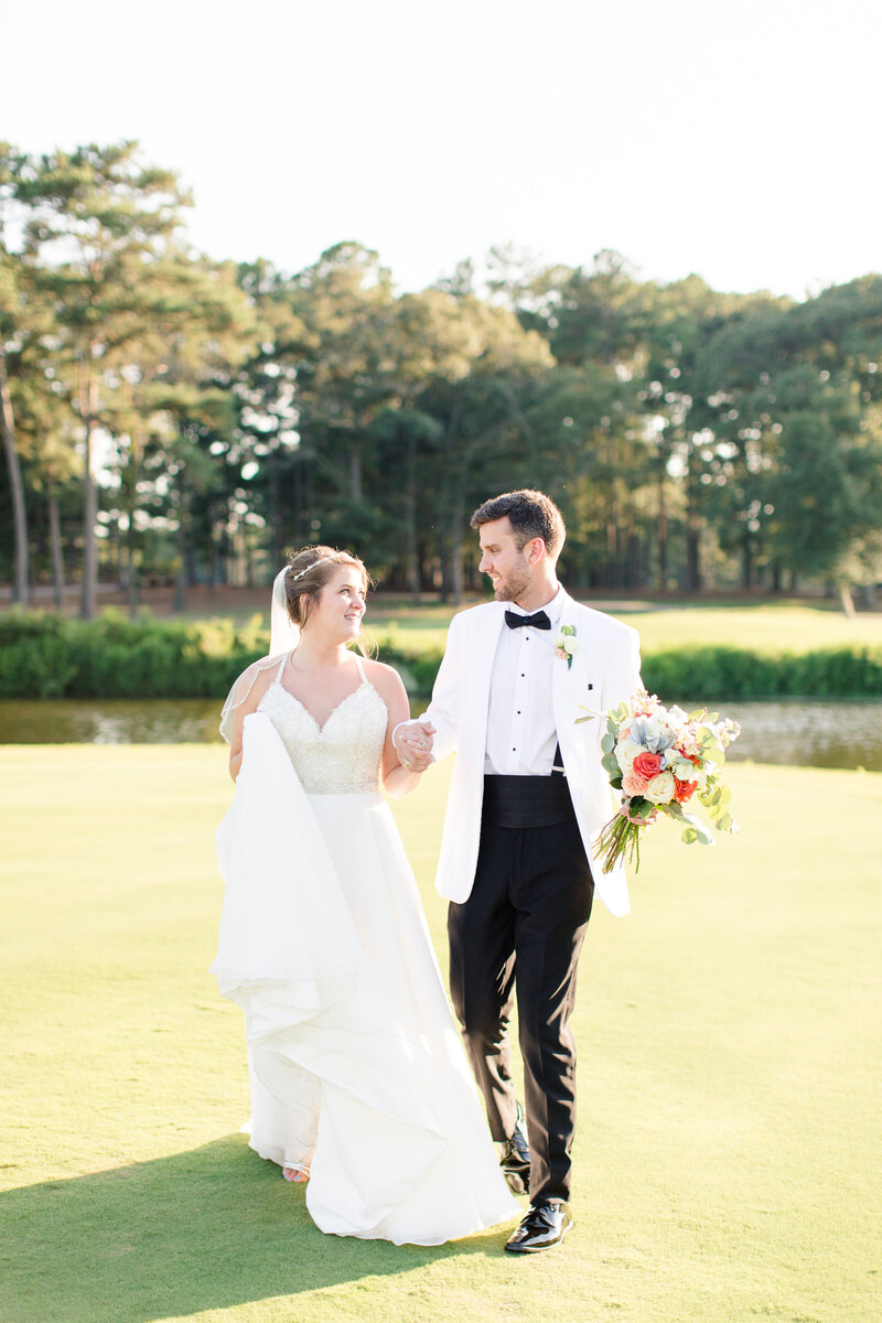 Bride and groom walking across a golf course