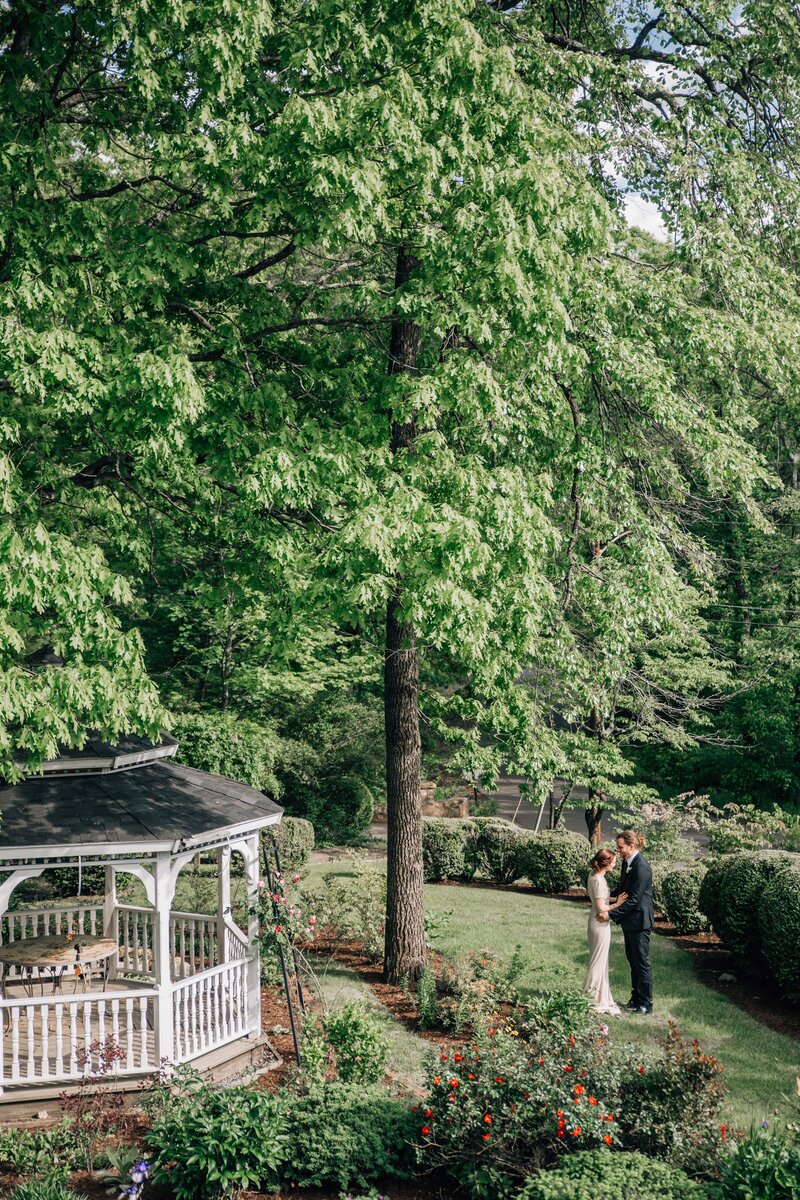 best Hampton Roads wedding photographers capture bride and groom in a secret garden at their wedding venue holding hands next to a gazebo