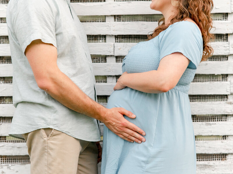 Close up portrait of husband holding the growing pregnant bump on his wife