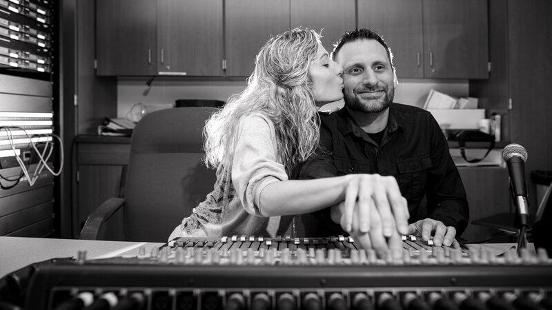 A theater-loving couple sitting together at the soundboard during their engagement session, celebrating their passion for the stage and storytelling.