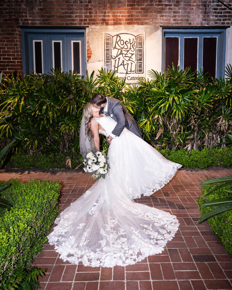 Bride and groom kissing in front of Rosy's Jazz Hall in New Orleans