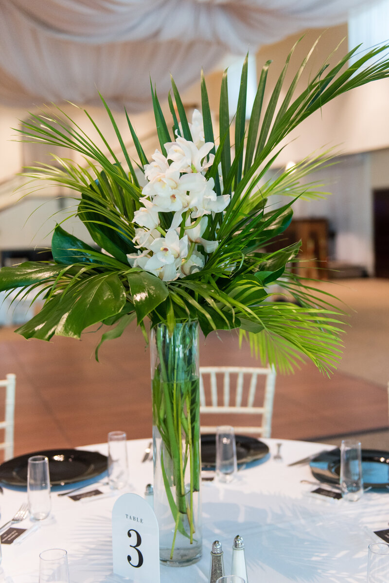 Elegant table settings with green foliage centerpieces by Jennifer’s Floral Designs.