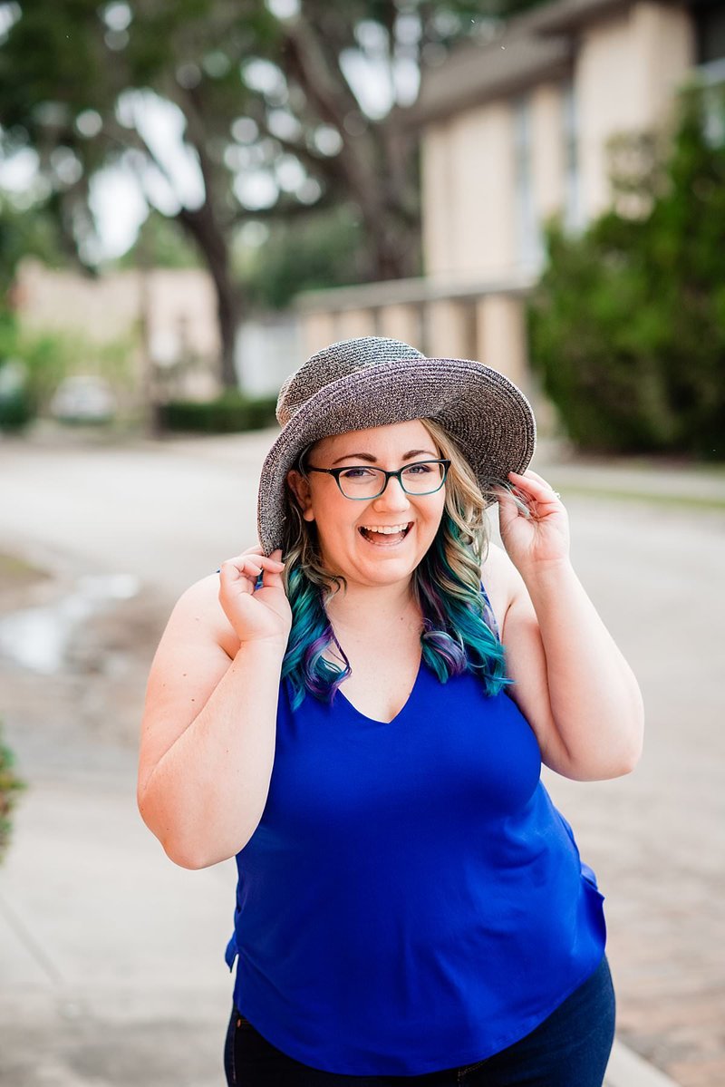 Mahlia wearing cobalt blue shirt and large floppy sun hat, laughing and smiling at the camera