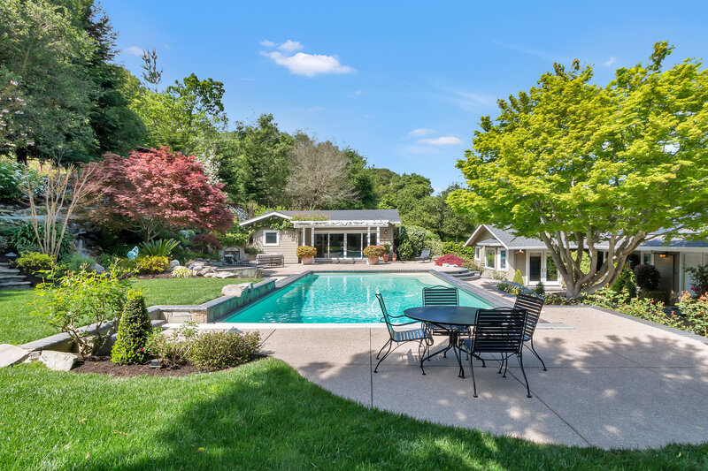 House with big blue pool surrounded by woods in summer