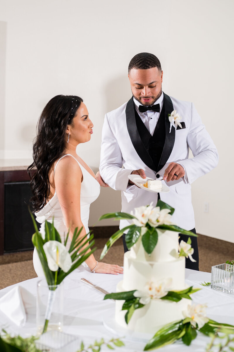 Bride and groom cutting their wedding cake by Las Vegas Custom Cakes during their reception at Emerald at Queensridge.