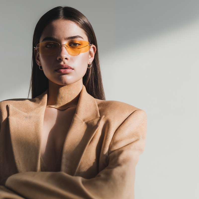 Powerful couture-style portrait of a woman in a tan blazer and amber glasses, showcasing the confidence and style of Jasmina Kimova’s reinvention experience