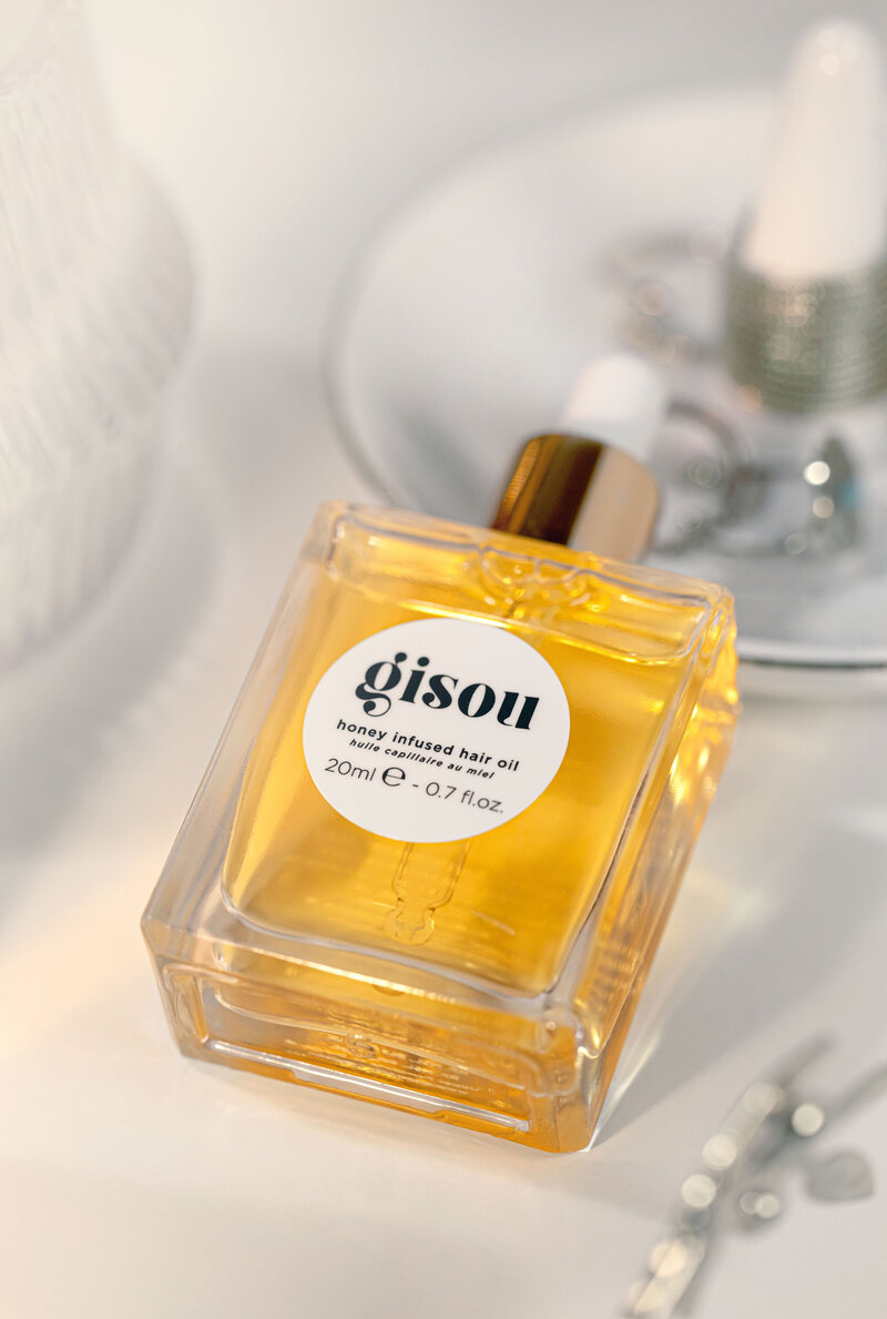 Photo lifestyle de l’huile capillaire Gisou sur fond blanc lumineux, réalisée par Studio Helloday.