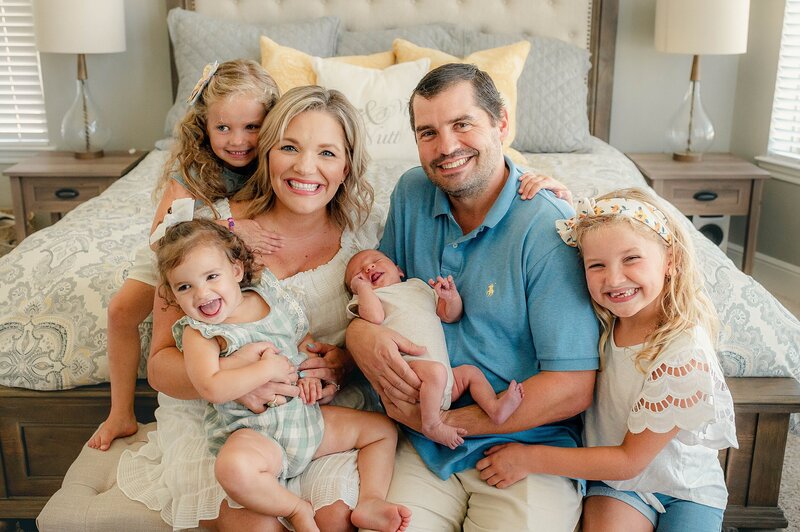 Young family of 6 smiling at camera at their Houston Newborn Photography session