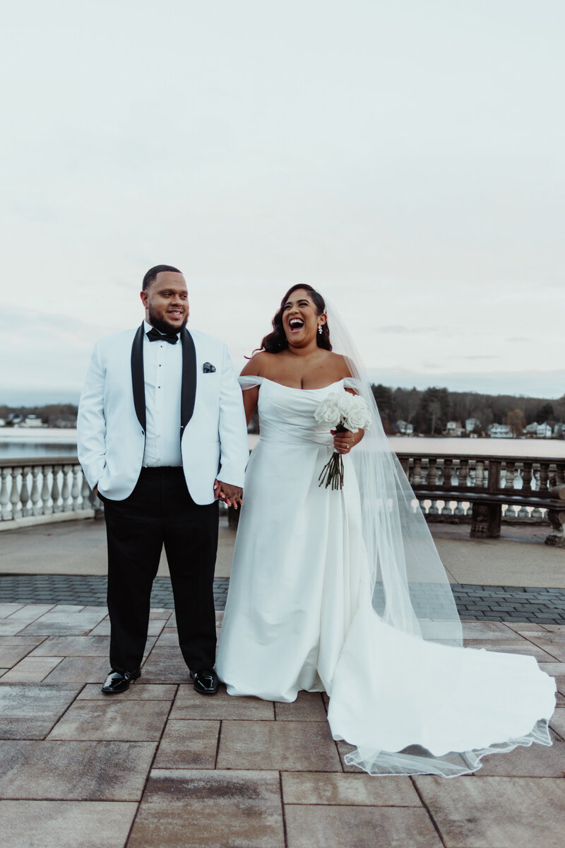 Bride and groom laughing with lake in the background