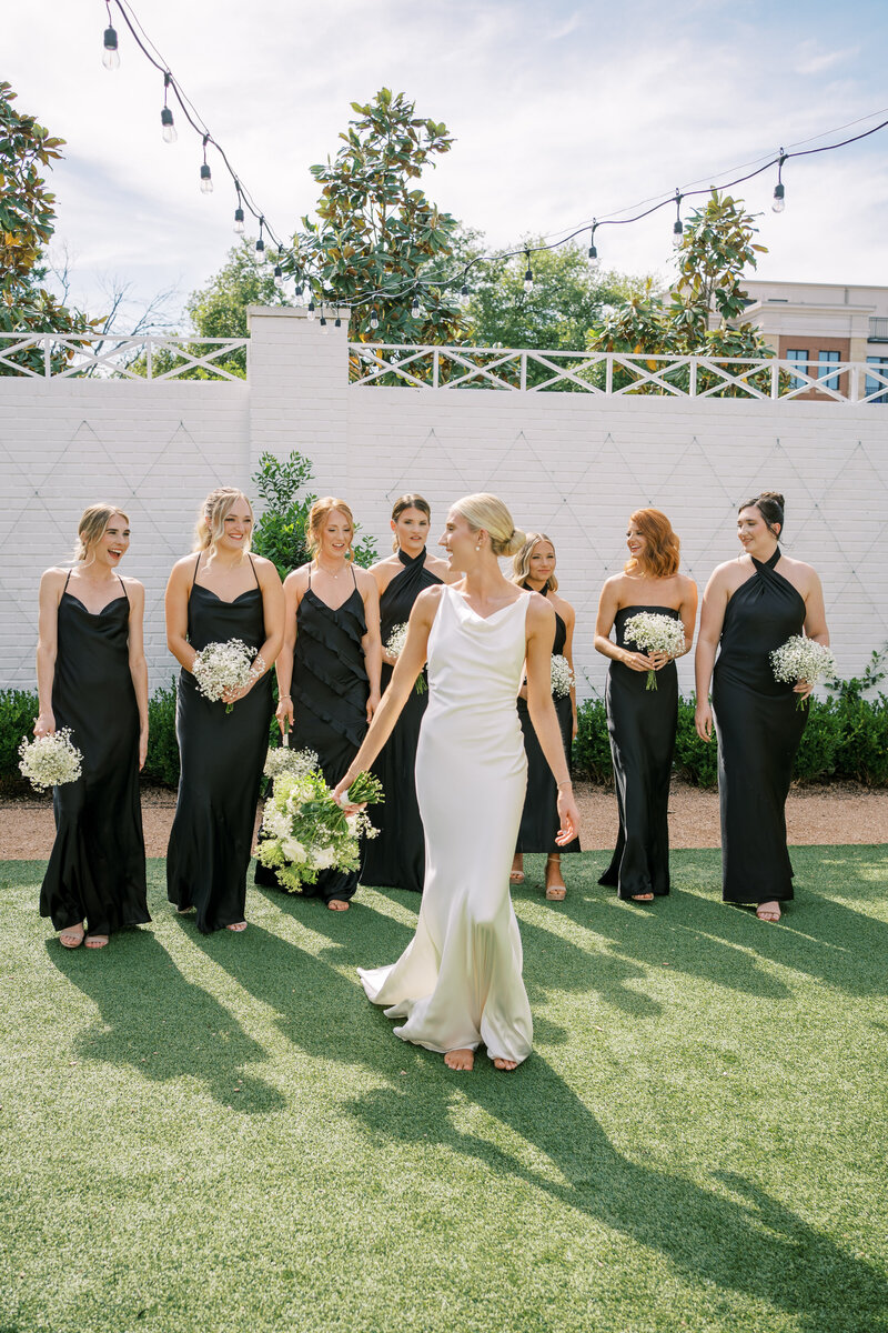 Bride walking with her bridesmaids in black dresses walking behind her