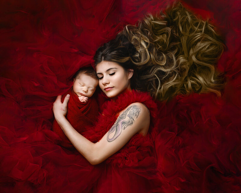 mom in red dress laying down with newborn in red wrap