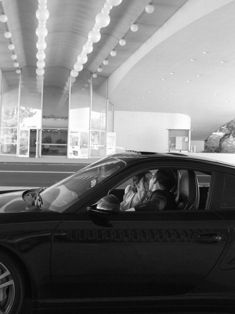 Black and white film photo of bride in car under Civic Center lights.