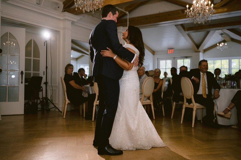 Couple sharing their first dance at a wedding reception with guests looking on.