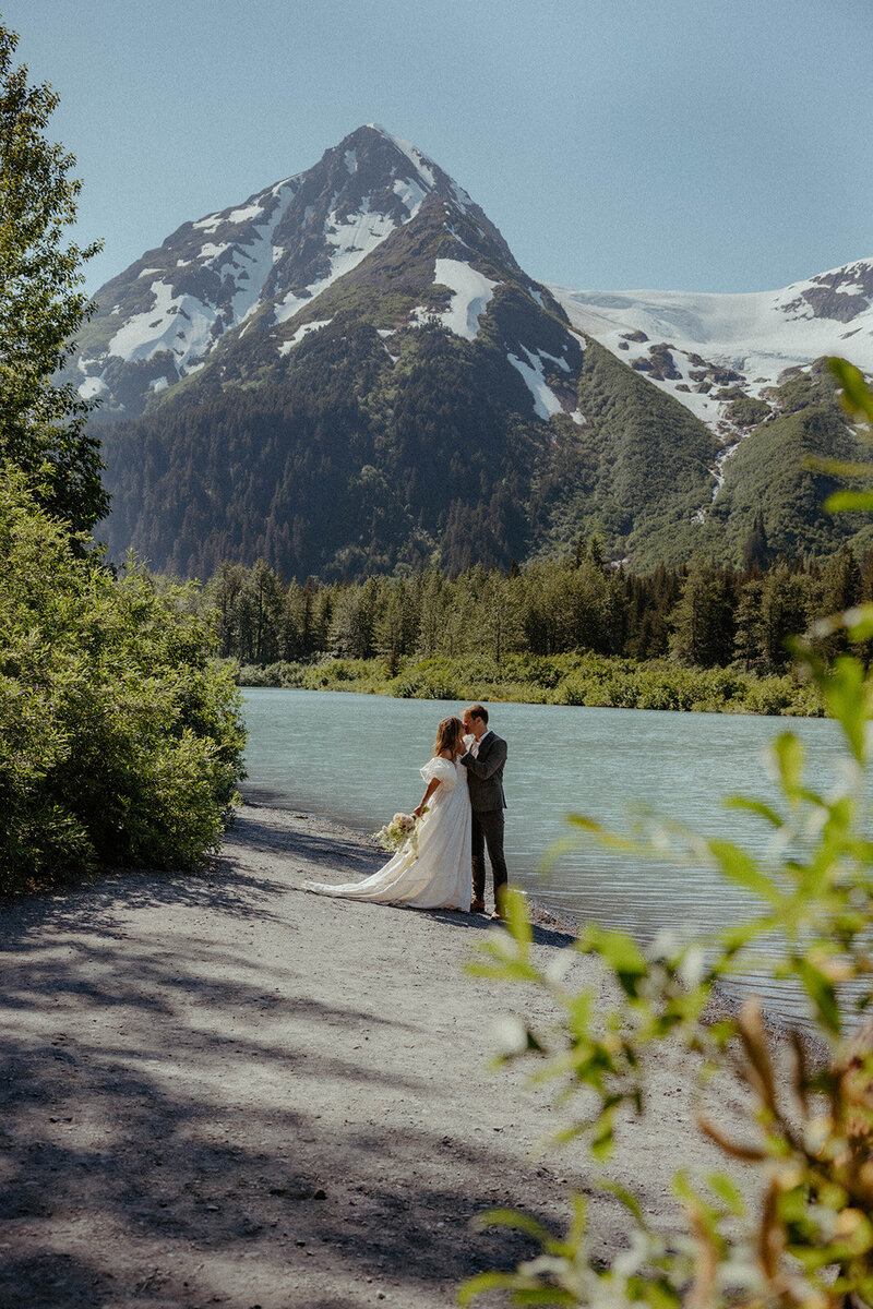 couples kissing each other at their elopement next to a lake in Alaska