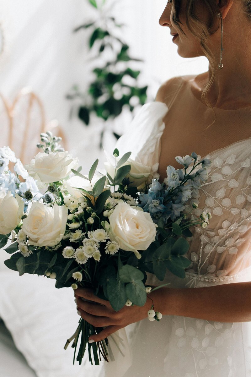 Bride in lace dress holding a beautiful bouquet, radiating elegance and grace on her wedding day.