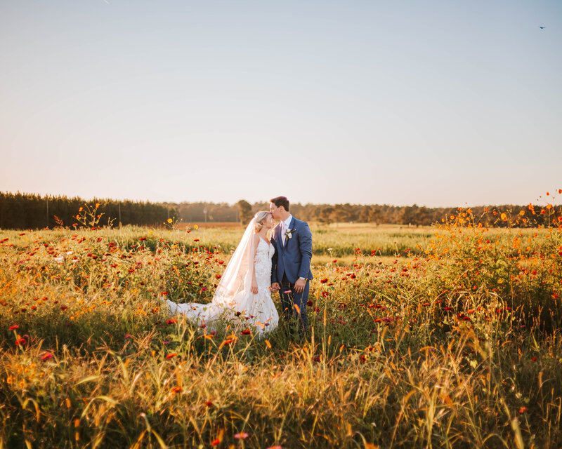 Bride and groom standing together in a Georgia wildflower field.