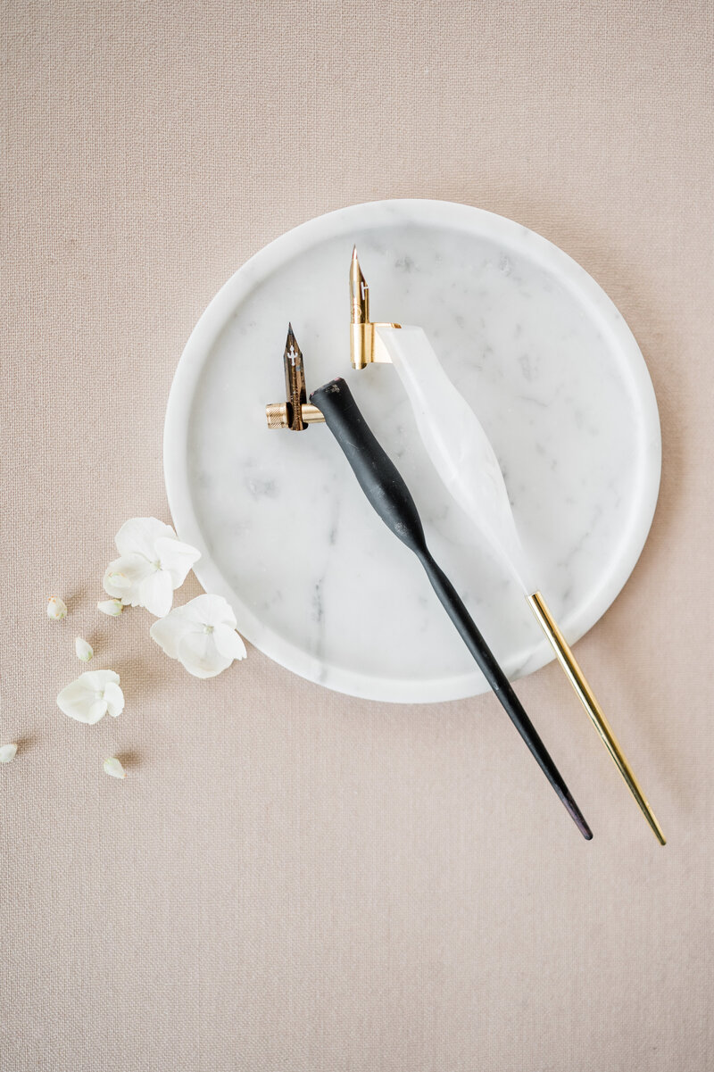 Two oblique calligraphy pens on a marble plate