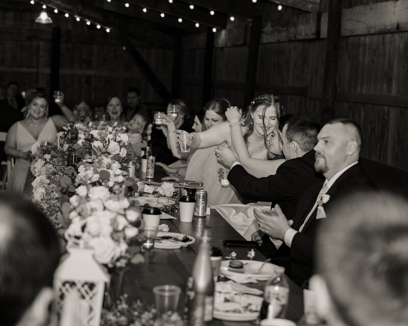A black and white image of a maid of honor hugging the bride after giving a wedding toast at a Dayton Ohio Catholic Wedding reception.