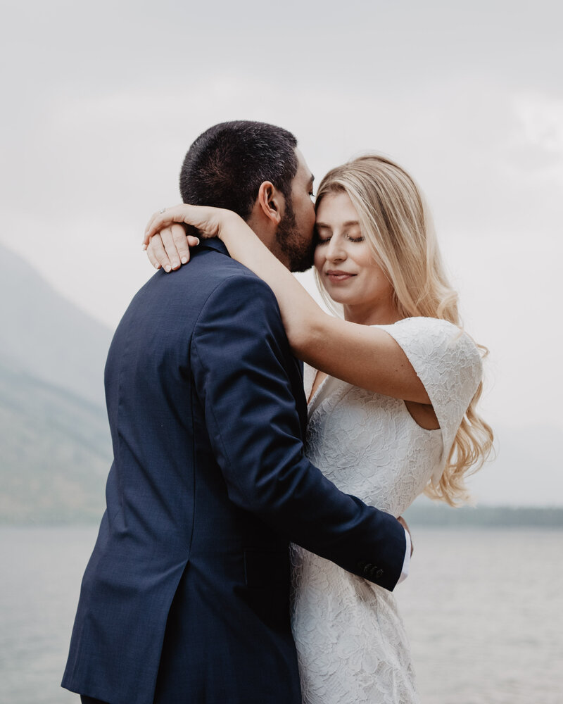 jackson hole photographers captures grand teton wedding pictures with bride holding her groom and closing her eyes as he kisses her romantically for their wyoming elopement