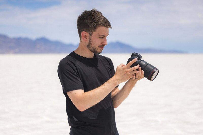 Man stands holding camera outside of the Utah Salt Flats