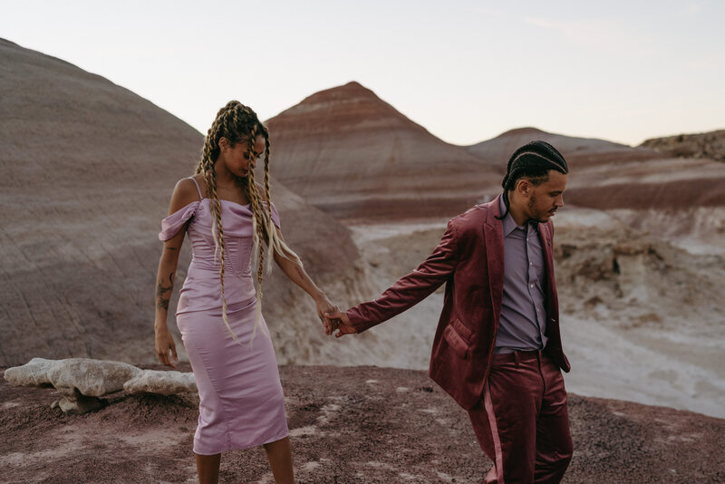 couple holding hands walking in the desert
