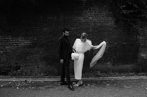 film black and white photo of a bride and groom in unposed wedding moment on a london street