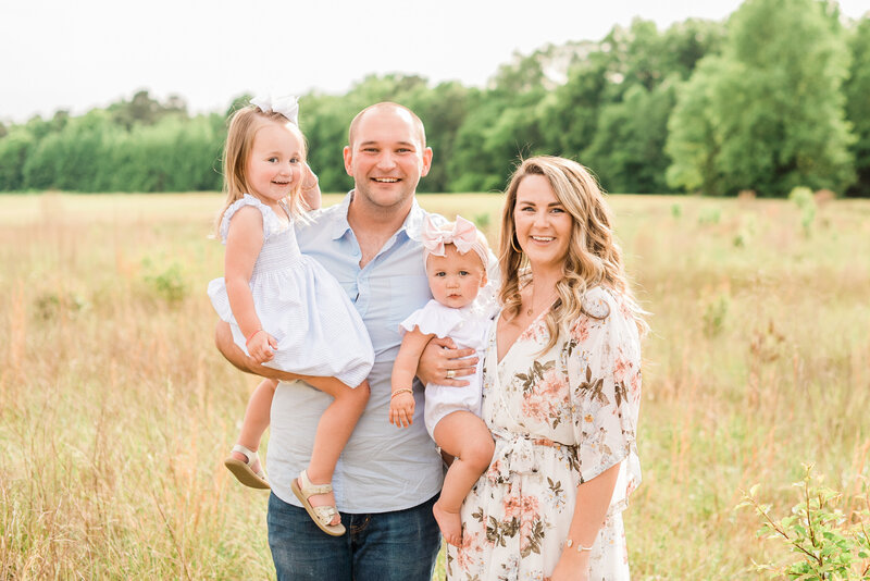 Family smiling for a portrait during a Raleigh NC maternity photo session. Photographed by Raleigh maternity photographers A.J. Dunlap Photography.
