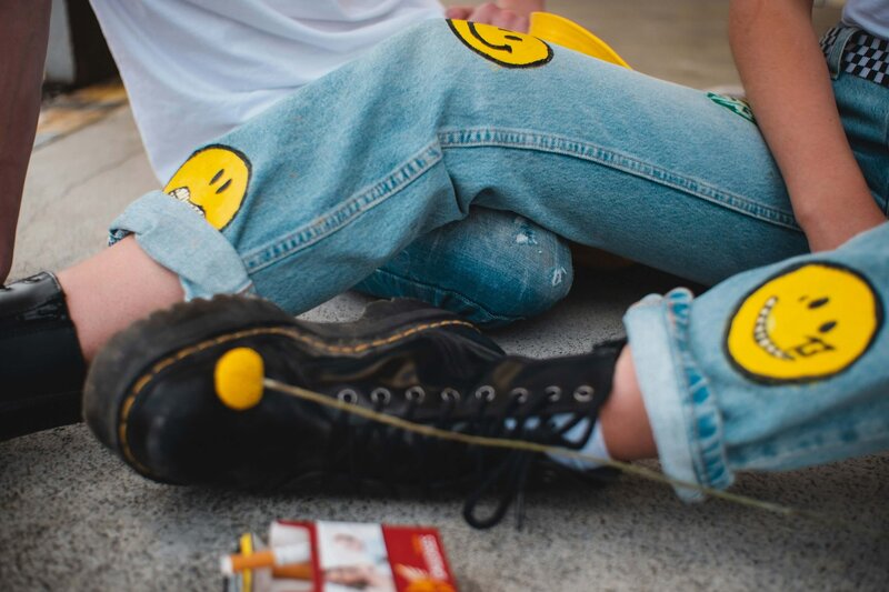 2 teans in jeans and black boots with smiley faces