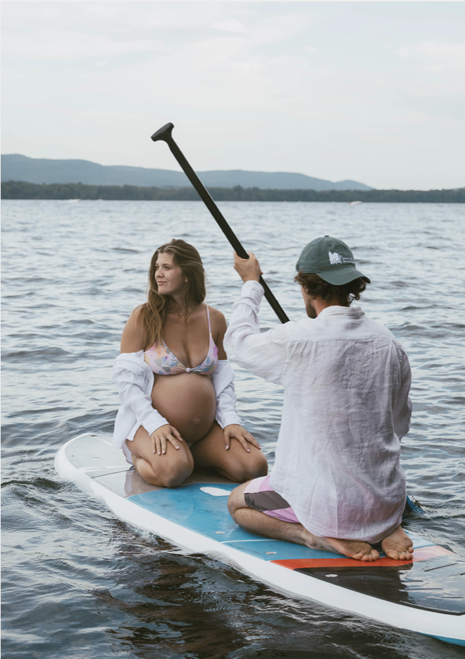 Adventurous maternity photo of pregnant woman on a paddle board