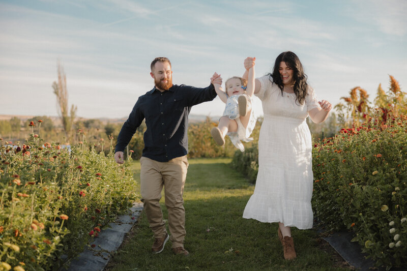 Brigette and Michael are swinging their daughter Isabella towards the camera, all smiling.