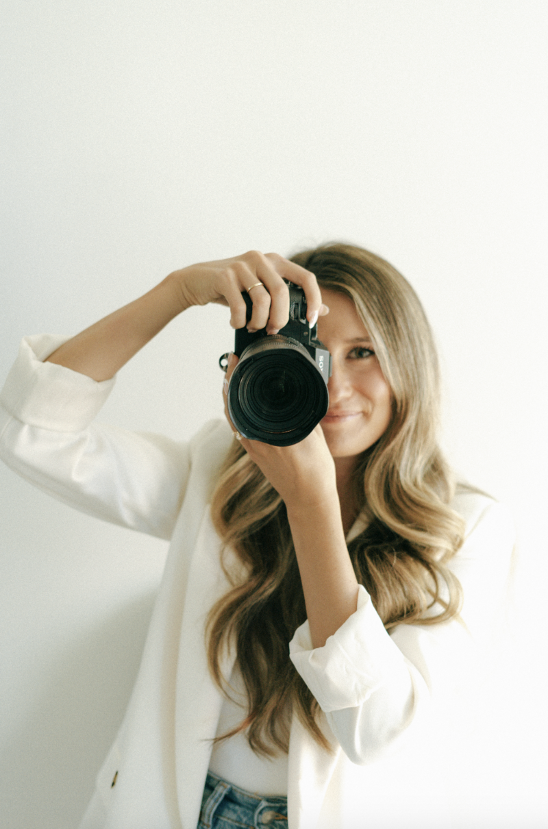 Photographer Kelsey holding a camera, ready to capture beautiful moments on a wedding day.