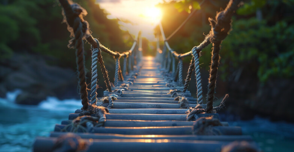 A photo of a bridge across water going towards the sun, representing the coaching journey from darkness to light