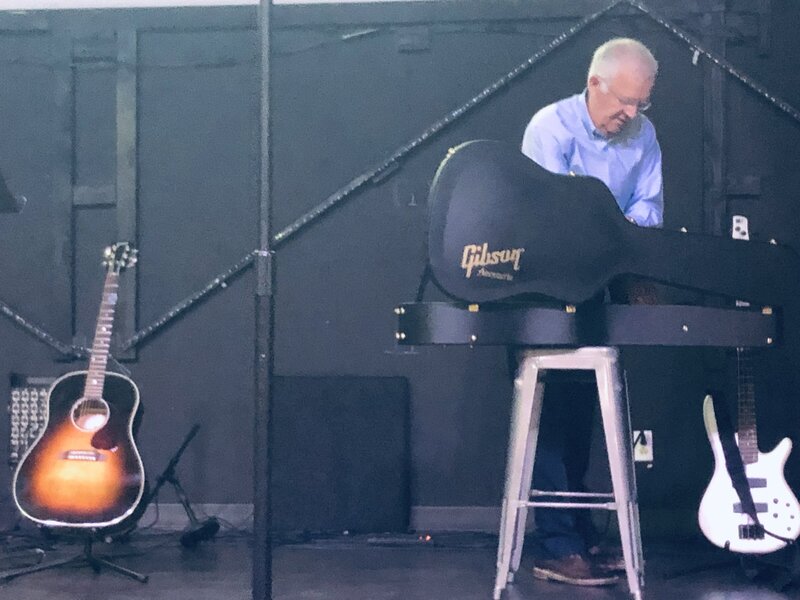 Amy's student Al Keigel on stage putting his guitar away after a performance. 