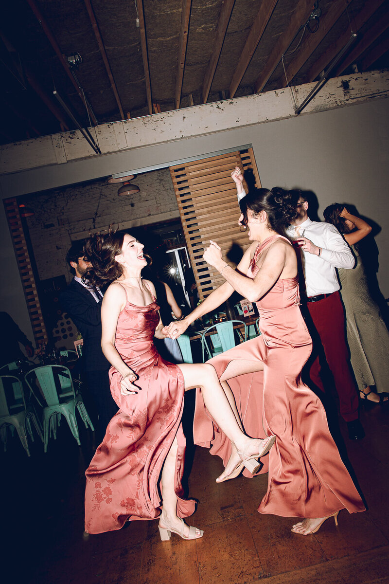 Two bridesmaids dance at The Joinery in Chicago during their friend's wedding