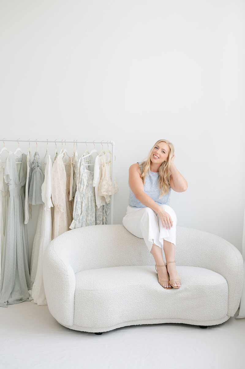 Deborah Jossick, photographer at Oak and Lore Studio, sits on the floor in her studio, focused on working on her computer. The space is filled with creative energy, with soft lighting and artistic elements surrounding her as she edits or plans her next project
