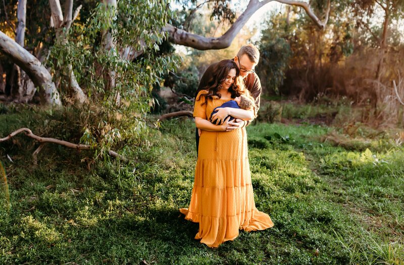 man and woman holding a baby in their arms during their new born photo session in Irvine
