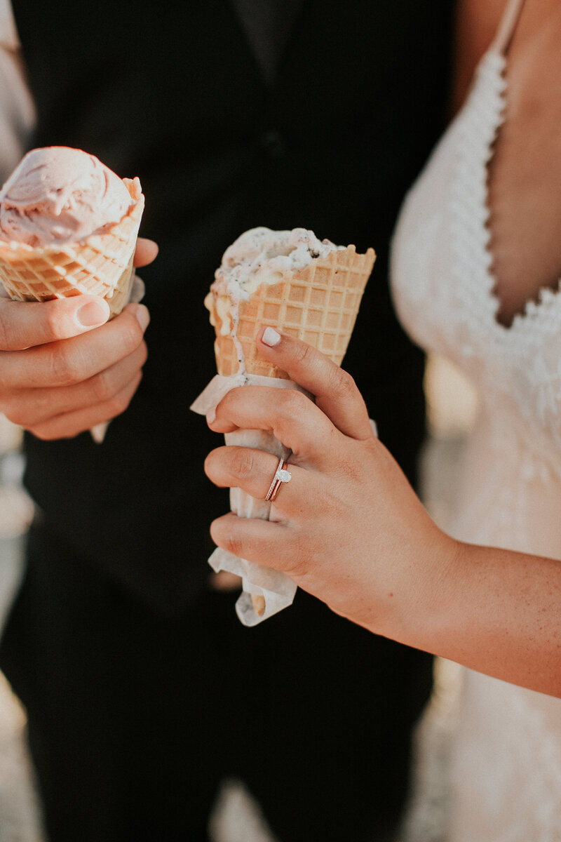 A bride and groom hold ice cream cones in their hands